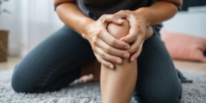 Person kneeling, holding knee in pain.
